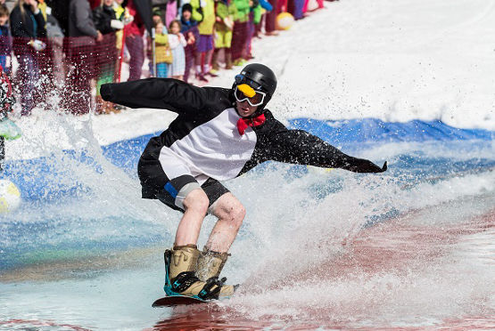 A costumed competitor skims across the pond on a snowboard.